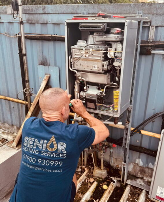 Senior Heating Services engineer repairing an external commercial boiler in Bournemouth